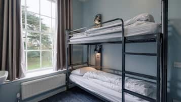 A bunk bed room with a window, radiator, and a wall-mounted light fixture.