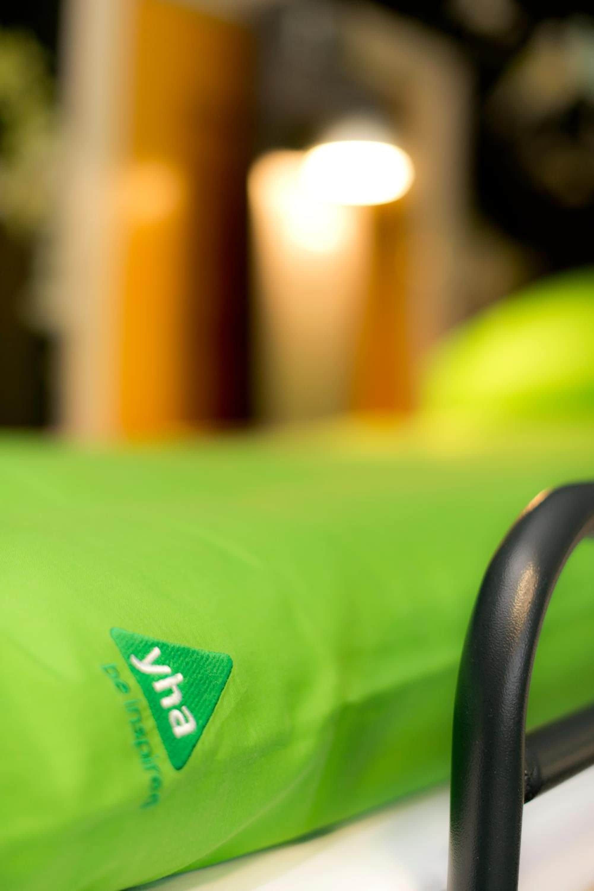 A close-up of a green object with a logo, possibly a bag or a piece of luggage, with a blurred background.