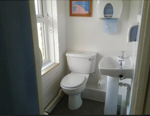 A small, compact bathroom with a toilet, sink, and window. - YHA Streatley - Hostel (Reading)