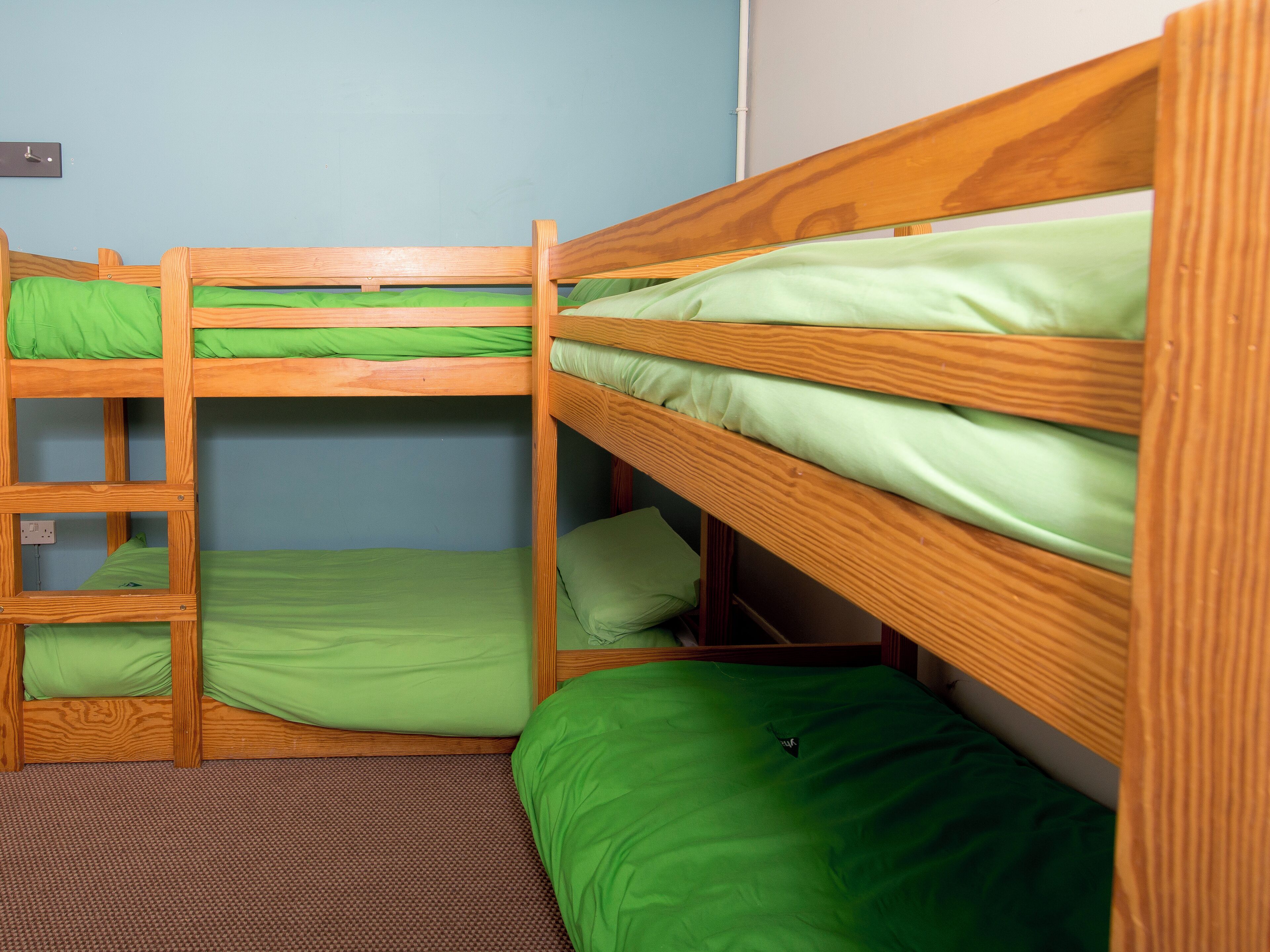 A bunk bed room with green bedding and a brown carpet.