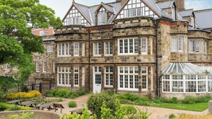 A historic stone building with multiple windows and a conservatory.
