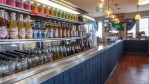 A bar area with shelves stocked with various bottles and glasses, a counter with a menu, and hanging pendant lights.