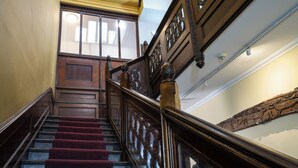 A grand staircase with a wooden handrail and a red carpeted landing.