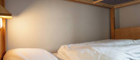 A bunk bed with white bedding and a wooden headboard.