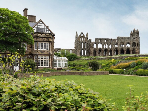 A historic building with a large garden in front.