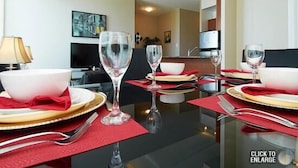 Un comedor con una mesa dispuesta para cuatro personas, con copas de vino, platos y cubiertos.