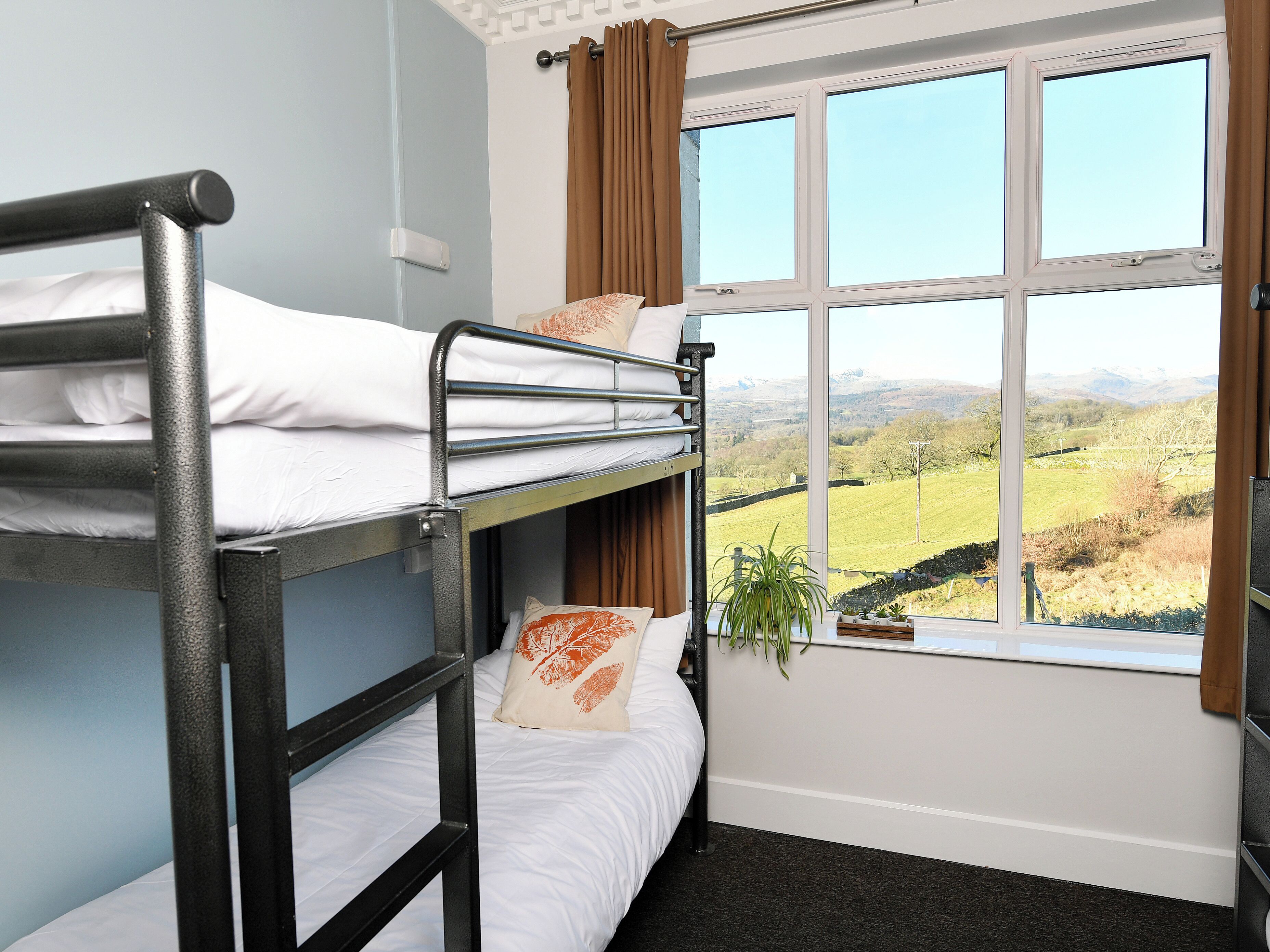A bunk bed room with a window offering a view of a green landscape.