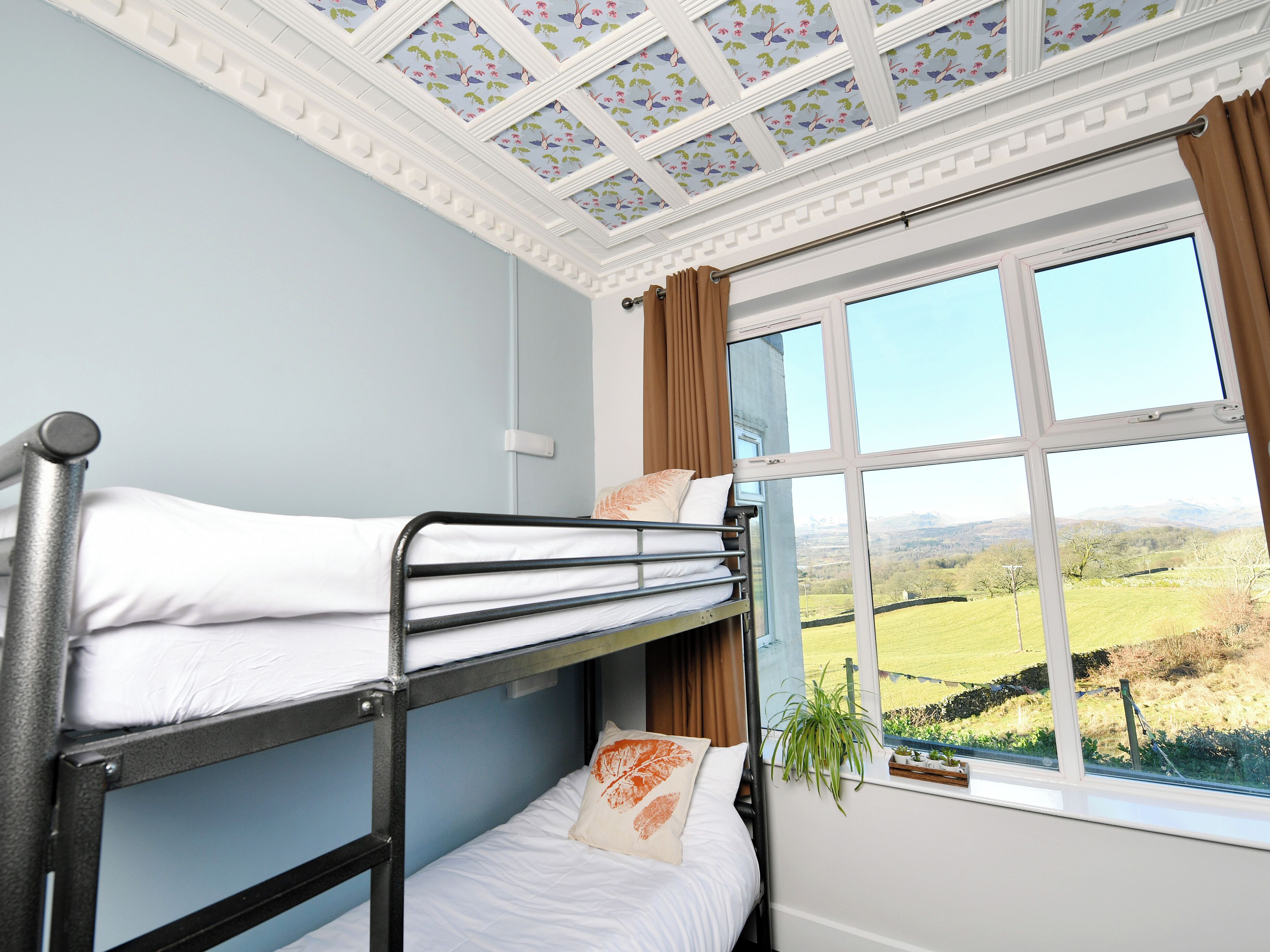 Une chambre avec des lits superposés et une fenêtre donnant sur un paysage verdoyant.