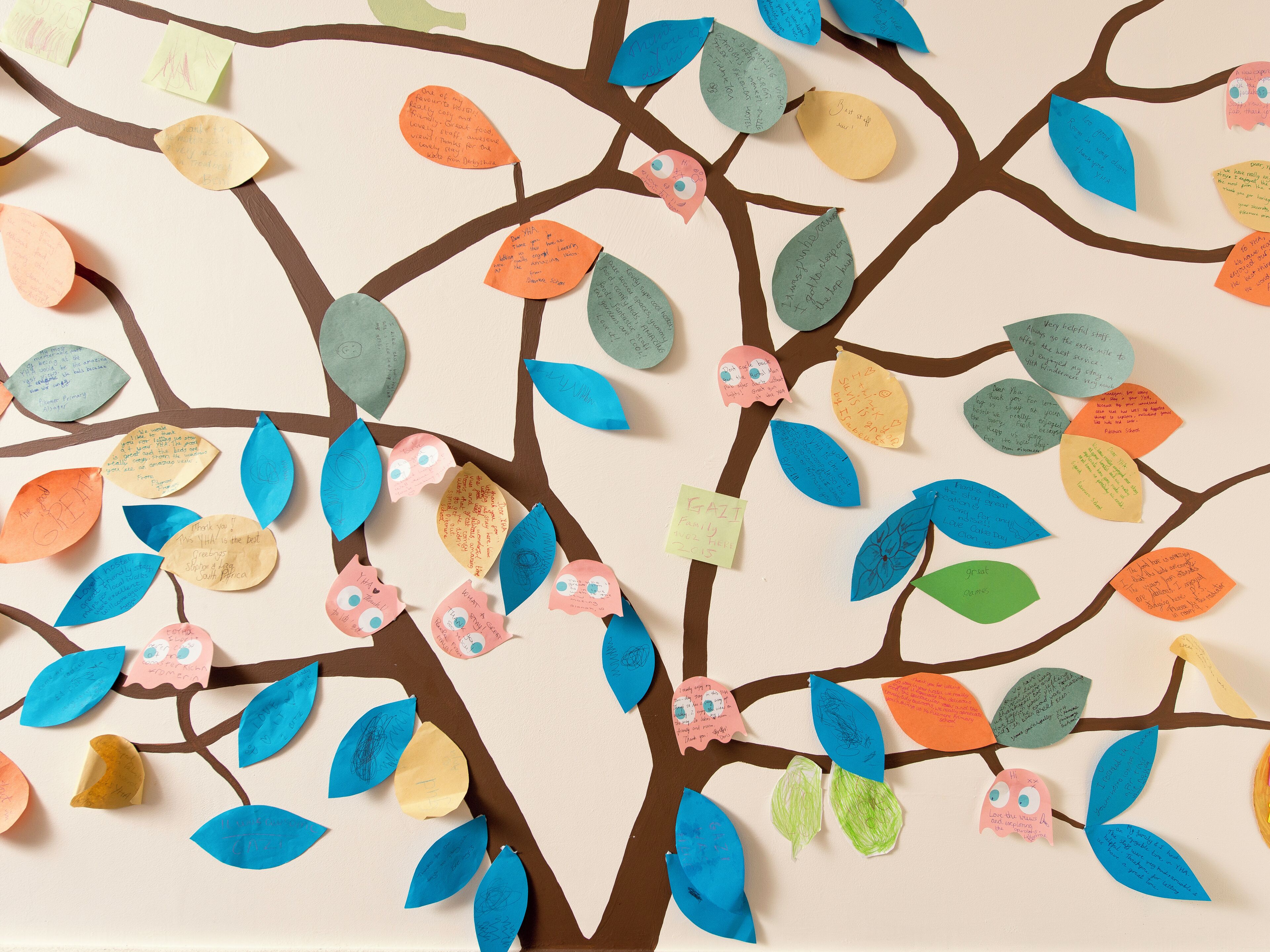 Un árbol con hojas de papel de colores y mensajes escritos.