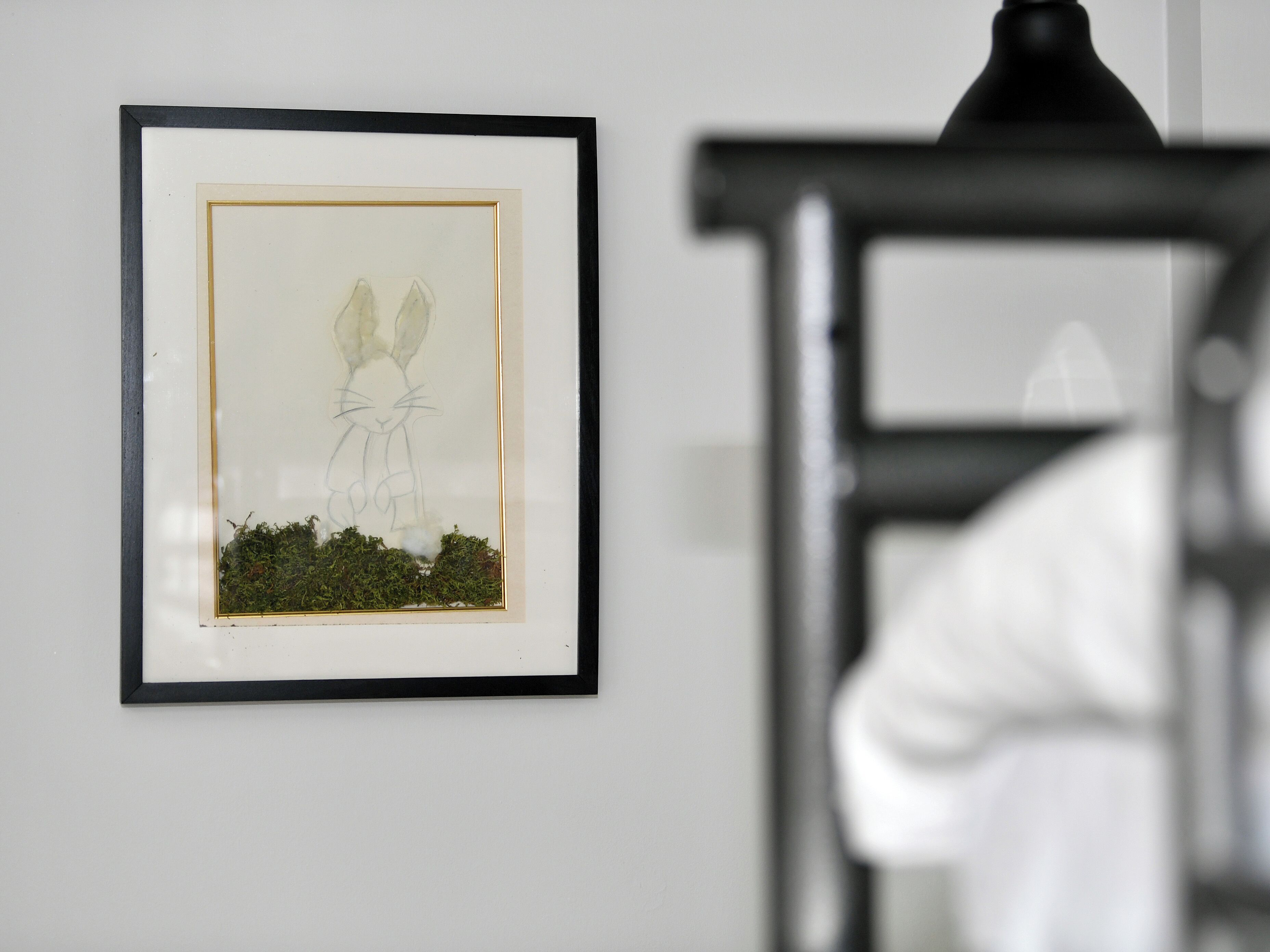 A framed artwork of a rabbit on a wall.