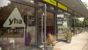 A YHA York building entrance with glass doors, a welcome sign, and outdoor seating area. - YHA York - Hostel (York)