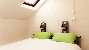 A small, well-lit room with a skylight, a bed with green pillows, and two wall-mounted coffee machines. - YHA York - Hostel (York)