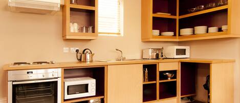 A compact kitchen with built-in appliances, wooden cabinetry, and a window.