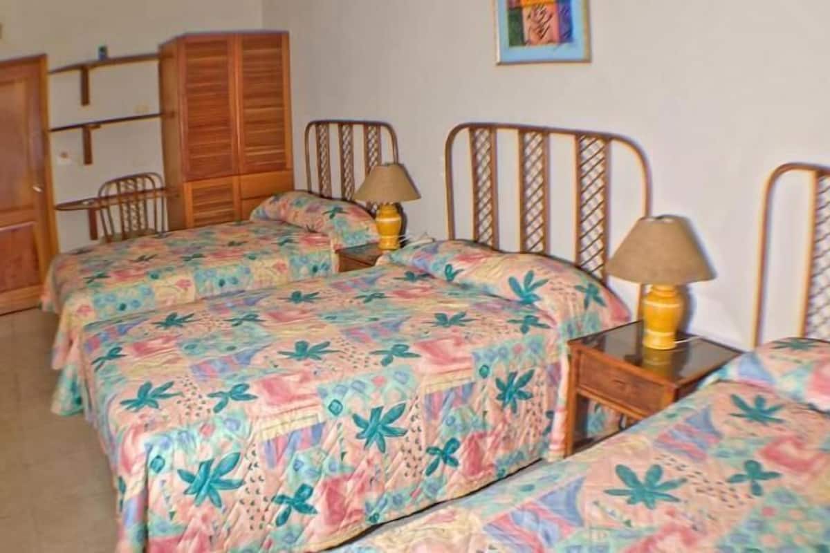 Une chambre avec deux lits, des têtes de lit en bois et une armoire.