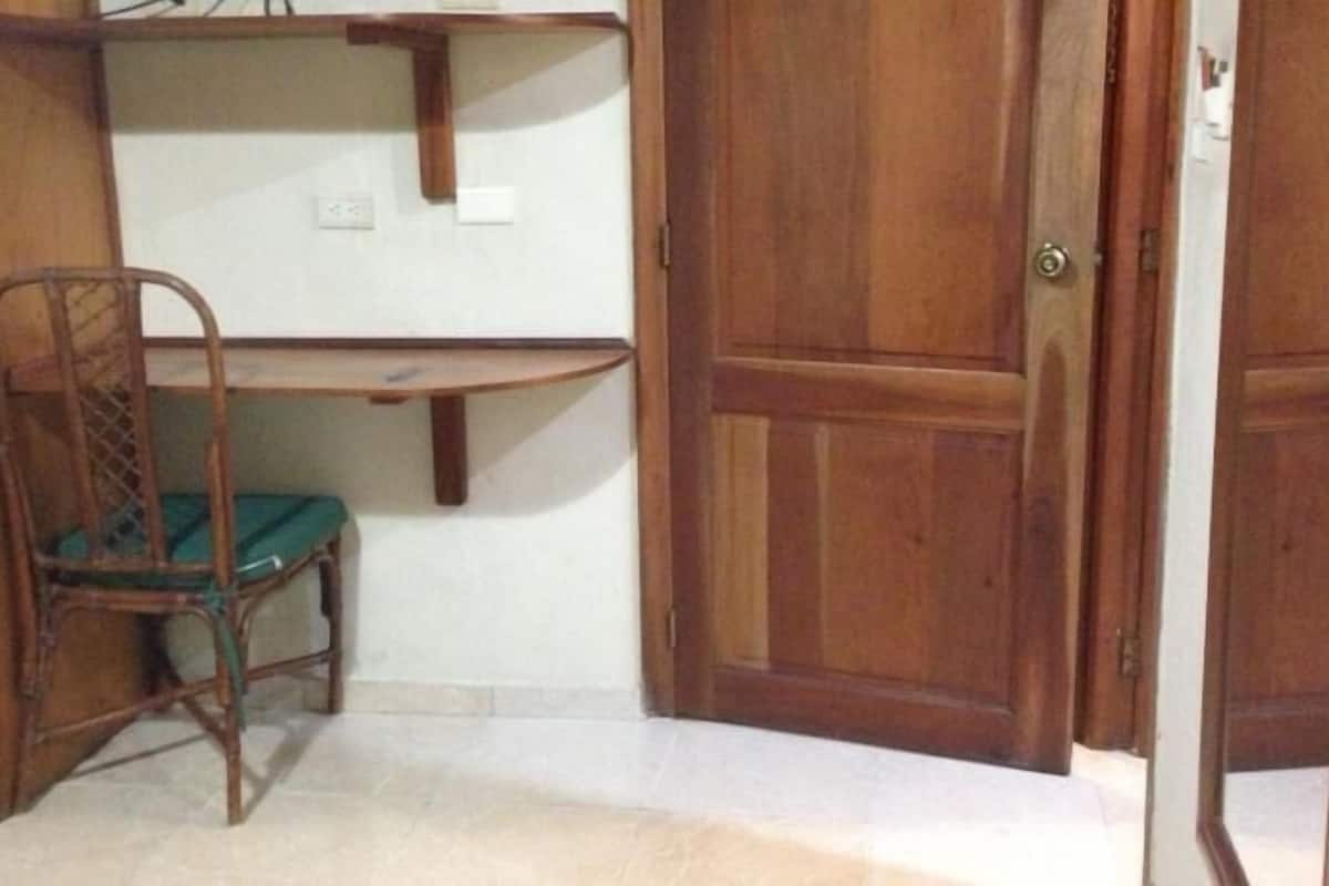 Une pièce avec une chaise en bois, un bureau en bois et une porte fermée.