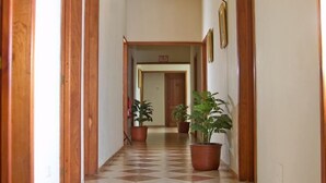 Un pasillo con puertas de madera, suelo de baldosas y plantas en macetas.