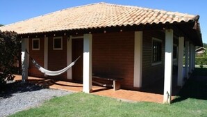 A single-story building with a tiled roof, a covered porch with white pillars, and a hammock tied between two columns. - Pousada Moinho de Vento (Bonito)