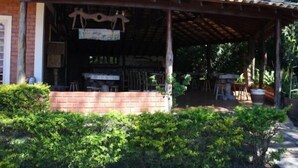 A rustic outdoor seating area with tables and chairs, surrounded by greenery. - Pousada Moinho de Vento (Bonito)