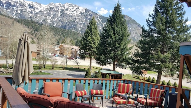 A deck with outdoor seating, a view of a parking lot, and mountains in the background.
