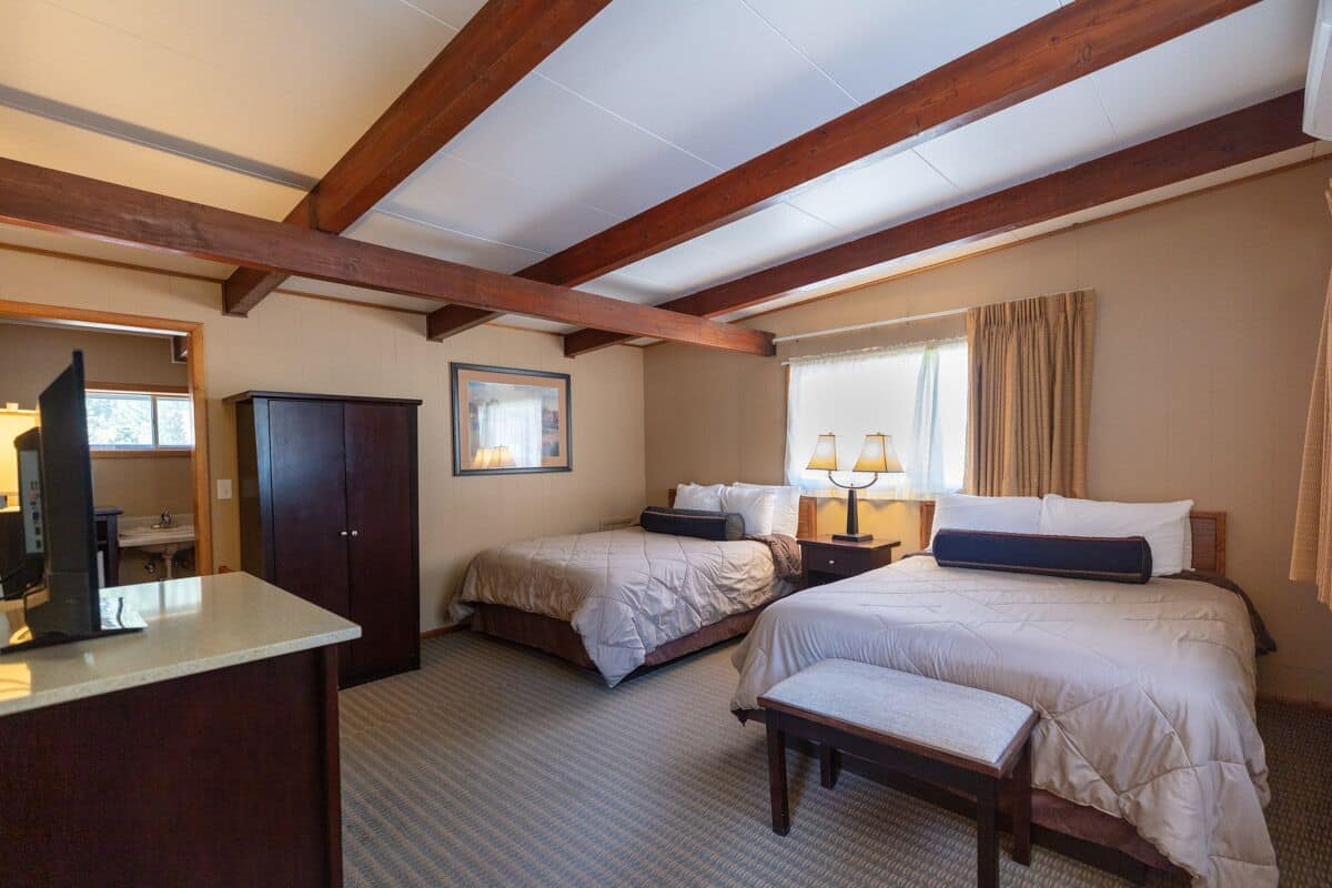 Habitación de hotel con dos camas, un escritorio y un espejo grande.