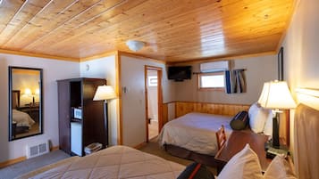 Habitación de hotel con dos camas, techo de madera, televisión, escritorio y espejo.