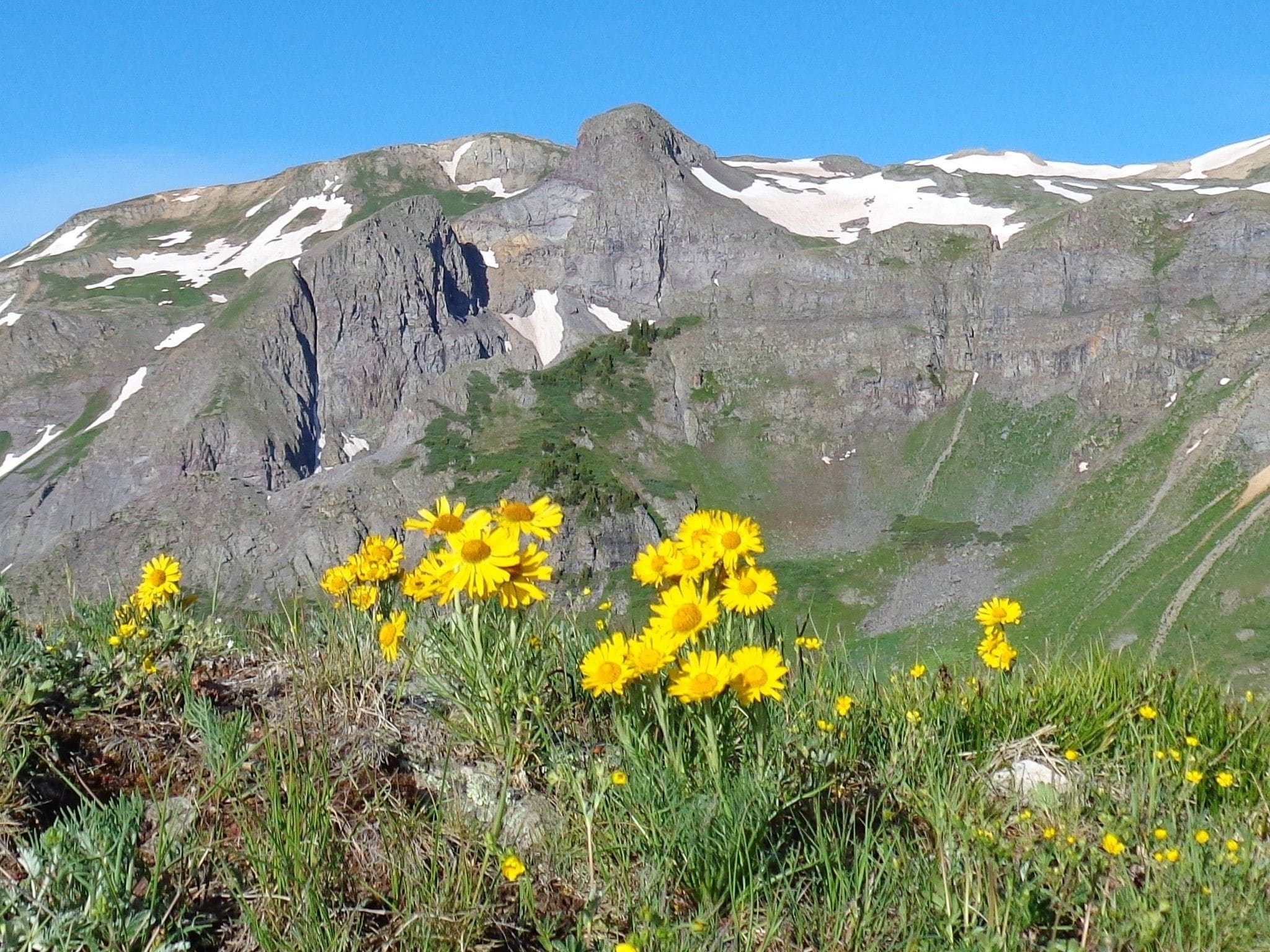 Paisagem montanhosa com primeiro plano rochoso e céu azul límpido.