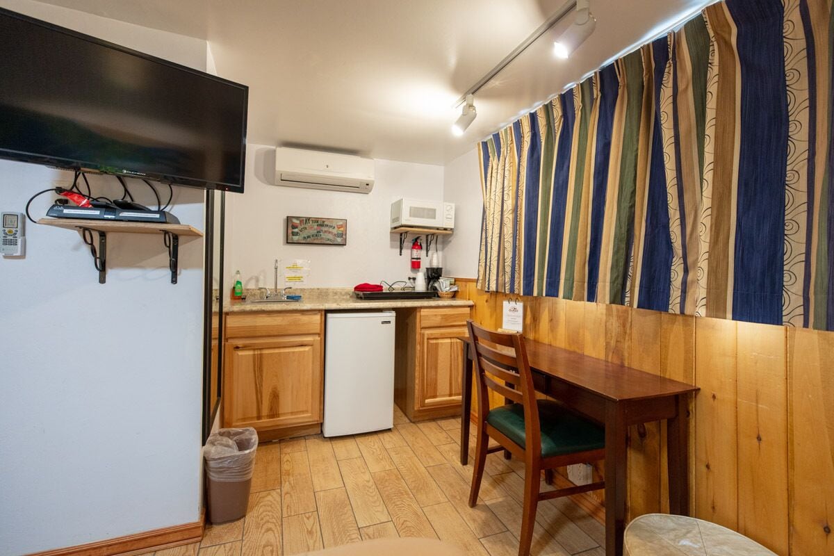 A compact kitchen with wooden cabinets, a built-in microwave, and a small refrigerator.