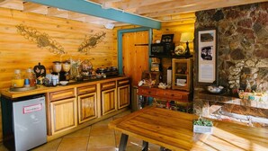 A rustic kitchen with wooden cabinets, a refrigerator, a stone wall, and a wooden dining table.