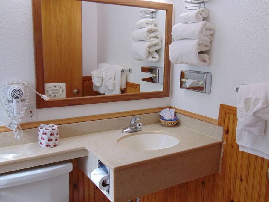 A bathroom with a sink, mirror, towel rack, and a toilet.