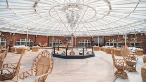 A spacious indoor area with a high ceiling and a central circular seating area surrounded by wicker furniture. - No Man's Fort (Portsmouth)