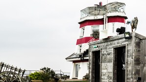 A pool with a wooden deck, a lighthouse, and a wooden building with a sign. - No Man's Fort (Portsmouth)