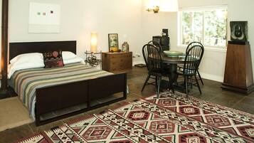 Un dormitorio con cama, mesita de noche, lámpara, cómoda, silla, mesa de comedor y alfombra.