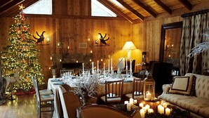 A cozy dining area with a wooden interior, a Christmas tree, and candles on the table. - Harmony Ridge Lodge (Nevada City)