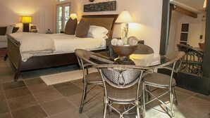 A hotel room with a bed, two bedside tables, a chair, a small table with a bowl, and a view of the outside. - Harmony Ridge Lodge (Nevada City)