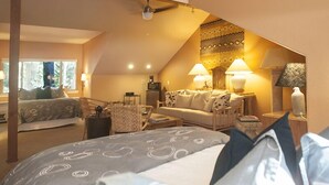 A cozy bedroom with a bed, a sofa, and a desk with lamps.