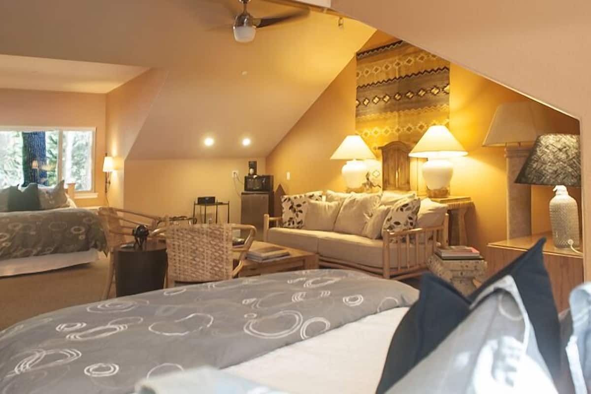 A cozy bedroom with a bed, a sofa, and a desk with lamps.