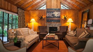 A cozy living room with wooden walls, a fireplace, two sofas, and two armchairs. - Harmony Ridge Lodge (Nevada City)