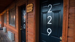 Un bâtiment en bois avec des portes numérotées, dont les portes numéros 230 et 229, et une enseigne au-dessus de la porte 230 indiquant « Sawtooth Suite ».