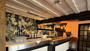 Un espace bar doté d’un comptoir en bois, de meubles blancs et d’un décor floral.