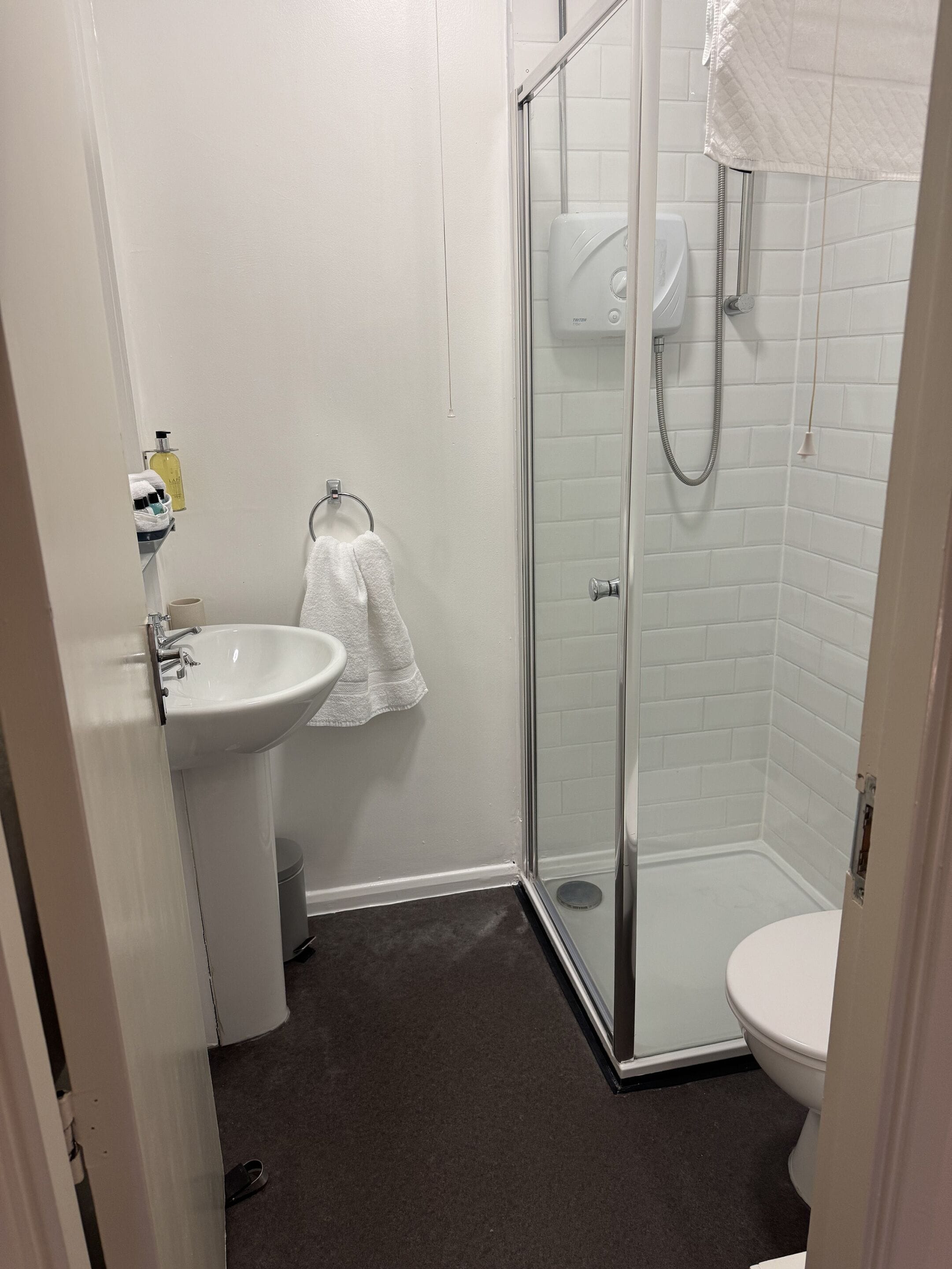 A bathroom with a glass-enclosed shower, a white sink, and a toilet.