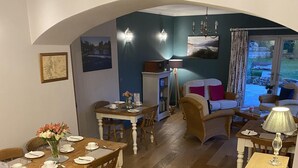 A dining area with a wooden table set for four, a sofa, and a lamp. - The Gables Bed & Breakfast (Matlock)