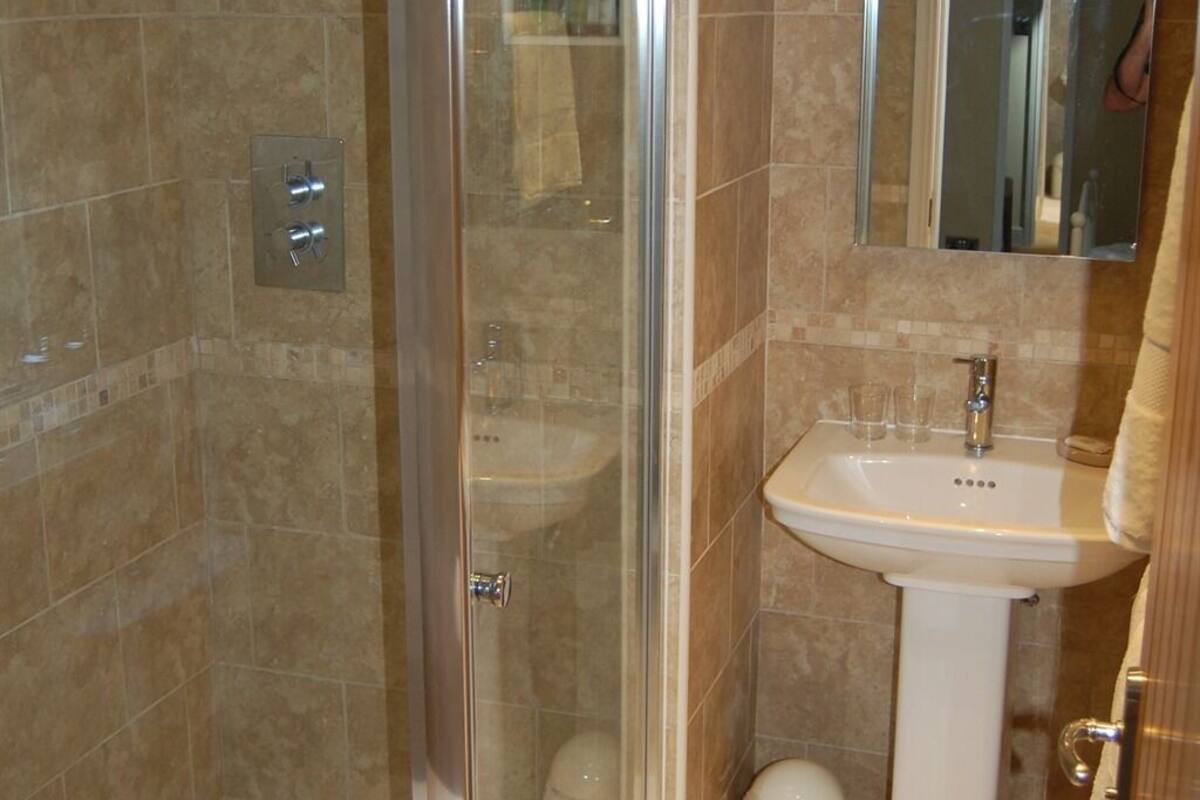A bathroom with a glass-enclosed shower, a white sink, and a mirror above the sink.