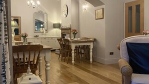 A spacious living room with a dining area, wooden flooring, and a chandelier. - The Gables Bed & Breakfast (Matlock)