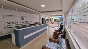 A reception area with a reception desk, wicker seating, and a view of the street outside.