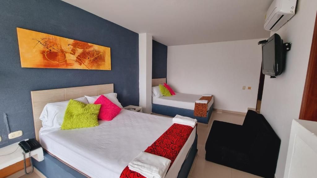 Ein Hotelzimmer mit zwei Betten, einem Flachbildfernseher und einem Bild an der Wand.
