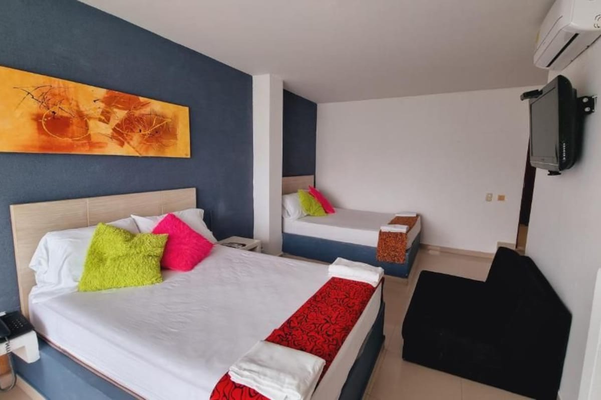 A hotel room with two beds, a flat-screen TV, a telephone, and a painting on the wall.