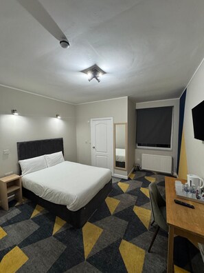 A hotel room with a bed, bedside table, chair, desk, and a large window. - OYO Weaste Hotel (Salford)