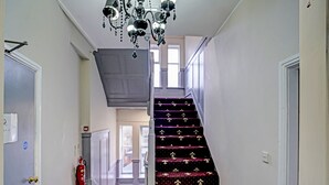 A staircase with a dark carpet featuring a floral pattern, white balusters, and a chandelier. - OYO Weaste Hotel (Salford)