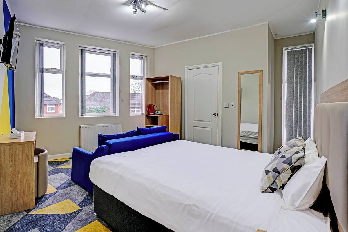 Une chambre à coucher comprenant un lit, un bureau, une chaise, une armoire et une fenêtre.
