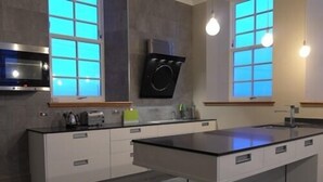 A modern kitchen with a central island, white cabinetry, and a built-in oven. - The Old School (Islay Island)